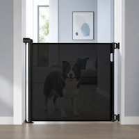 Black retractable pet gate mounted across a doorway with a dog safely behind it View 13